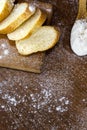 Flour in a wooden spoon  sliced French baguette on a wooden board and sprinkled with flour on a wooden table Royalty Free Stock Photo