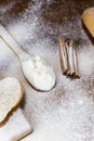 Flour in a wooden spoon  sliced French baguette on a wooden board and cinnamon sticks heavily floured on a wooden table. Royalty Free Stock Photo