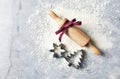 A floured marble work surface, cutters and a rolling pin with red ribbon. Christmas baking. Flatlay. Copy space