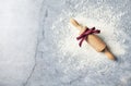 A floured marble work surface and a rolling pin with red ribbon. Christmas baking. Flatlay. Copy space