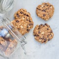Flourless gluten free peanut butter, oatmeal and chocolate chips cookies in glass jar, top view, square