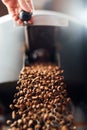 The flow of coffee beans from hand open flap of the cooling mixer of roasting machine Royalty Free Stock Photo