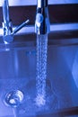 Flow of water in a metal sink on a modern kitchen. Toned Royalty Free Stock Photo