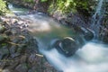 The flow of a waterfall containing mossy black stones Royalty Free Stock Photo