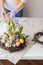 Flower arrangement in a nest with easter eggs on a white table Royalty Free Stock Photo