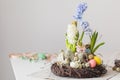Flower arrangement in a nest with easter eggs on a white table Royalty Free Stock Photo