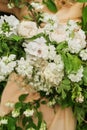 Flower arrangement of white flowers on the dress. bride holds a wedding bouquet close-up