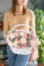 Flower arrangement in Wicker basket. Beautiful bouquet of mixed flowers in woman hand. Floral shop concept . Handsome