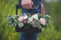 Flower arrangement in a wooden box with spray pink roses, succulent, eustoma, white hypericum, eucaliptus in man& x27;s hands Royalty Free Stock Photo