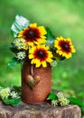 Flower arrangement with yellow and orange globular or Black Eyed Susan flowers and ivy blossom in rusty tins with rustic heart Royalty Free Stock Photo