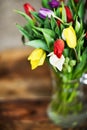 Flower background: bouquet of colorful tulips in a glass vase on a natural wooden background, postcard, mocap for mother Royalty Free Stock Photo