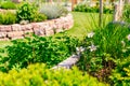 Flower bed with green lawn and herb spiral made of bricks for a small garden Royalty Free Stock Photo