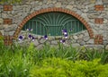 A flower bed with irises near a stone paved fence with a decorative lattice. Royalty Free Stock Photo