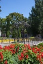 Flower bed in the public garden, wrought iron gazebo