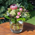 Flower bouquet with protea, sedum and pink roses. Beautiful summer flower arrangement in glass vase. Royalty Free Stock Photo