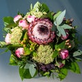 Flower bouquet with protea, sedum and pink roses. Beautiful summer flower arrangement in glass vase. Top view. Royalty Free Stock Photo