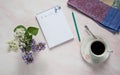 A notepad with a to-do list, a pencil, a cup of black coffee, and spring lilac flowers on a pastel pink marble background. Royalty Free Stock Photo