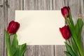 Paper blank and a spring bouquet of red tulips on a wooden background. Royalty Free Stock Photo