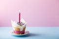 Flower cupcake  with single candle on blue  table on pink background. Beautiful sponge cup cakes decorated with buttercream lilac Royalty Free Stock Photo