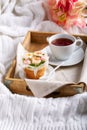 Flower cupcakes and cup of tea on wooden tray on white plaid.  Beautiful sponge cup cakes decorated with buttercream roses on Royalty Free Stock Photo