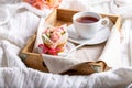 Flower cupcakes and cup of tea on wooden tray on white plaid.  Beautiful sponge cup cakes decorated with buttercream roses on Royalty Free Stock Photo