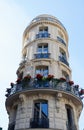 The flower-decked facade of traditional French house with typical balconies and windows. Paris.