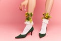 Close up portrait of beautiful female feet wearing heels with bloom inside over pink studio background. Flower Royalty Free Stock Photo