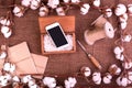 Flower design with fluffy dried cotton bolls gift boxes, white smartphone and jute rope hank over rough brown burlap Top