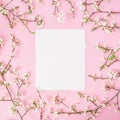 Flower frame with white flowers and paper vintage card on pink background. Flat lay, top view. Royalty Free Stock Photo