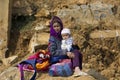 Flower Hmong grandmother sitting in the sun on rock with chubby baby on her knees