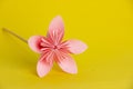 Flower made of pink paper on a yellow uniform background. DIY concept. Children`s creativity