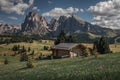 Flower meadows with wooden cabins at Alpe di Siusi during summer with view to mountains of Plattkofel and Langkofel in Dolomites Royalty Free Stock Photo