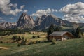 Flower meadows with wooden cabins at Alpe di Siusi during summer with view to mountains of Plattkofel and Langkofel in Dolomites Royalty Free Stock Photo
