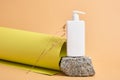 flower and mock up blank white bottle with dispenser for cosmetics on stone, rolled green textured paper