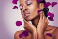 Flower, petal and black woman in studio for makeup, beauty or wellness on purple background. Floral, skin and Africa