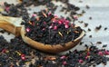 Black blended tea with flower petals and dried fruit on a wooden spoon. Royalty Free Stock Photo