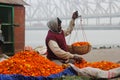 A flower seller weighing marigolds for sale.