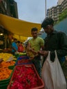 A flower shop vendor and customer exchanging money while standing in the flower market of Dadar, Mumbai