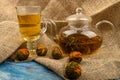 Flower tea brewed in a glass teapot, a glass of flower tea and balls of flower tea on a background of rough homespun fabric. Close Royalty Free Stock Photo