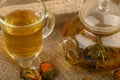 Flower tea brewed in a glass teapot, a glass of tea and balls of flower tea on a background of rough homespun fabric. Close up