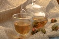 Flower tea brewed in a glass teapot, a glass of tea and balls of flower tea on a background of rough homespun fabric. Close up