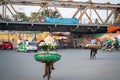 Flower vendor on Hanoi street at early morning with Long Bien old metal bridge on background Royalty Free Stock Photo