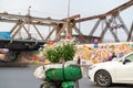 Flower vendor on Hanoi street at early morning with Long Bien old metal bridge on background Royalty Free Stock Photo
