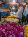 A flower vendor standing near baskets of flowers in Dadar flower market
