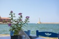 Flower and view from the cafe to sea and Venetian Harbor with lighthouse of Chania Old Town. Crete island of Greece Royalty Free Stock Photo