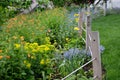 Flowerbed with colorful perennials and wooden fence posts with ropes in the park