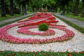 A flowerbed with pink flowers in the form of a spiral in a city park against a background of green trees Royalty Free Stock Photo