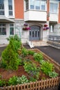 A flowerbed and planters of bright petunia flowers and various plants in front of the entrance of a residential building. Royalty Free Stock Photo