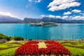 Flowerbed of the Swiss flag with boat cruise on the Thun lake and Alps mountains, Oberhofen, Switzerland. Swiss flag made of Royalty Free Stock Photo