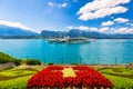 Flowerbed of the Swiss flag with boat cruise on the Thun lake and Alps mountains, Oberhofen, Switzerland. Swiss flag made of Royalty Free Stock Photo